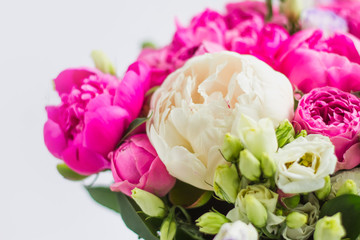 Arrangement of flowers in a hat box. Bouquet of peonies, eustoma, spray rose in a pink box with an oasis on a white background