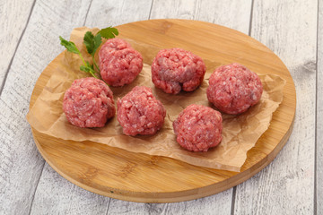 Raw meatball over wooden background