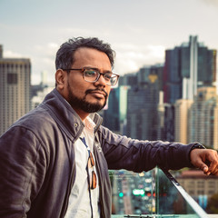 Young bearded man looking out over the city skyscrapers