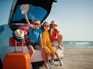 happy children girls friends sisters on the car ride to summer trip.