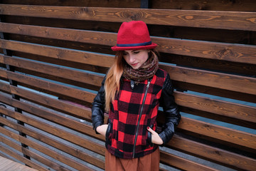 Sensual woman in a red bowler hat with long hair on wooden background. Autumn fashion.