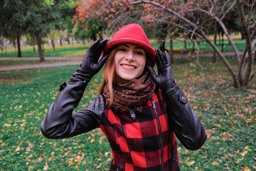 Sensual woman in a red bowler hat with long hair walking in park. Autumn fashion.