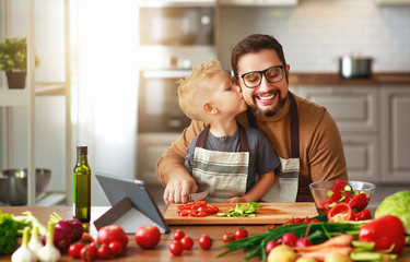 happy family father with son preparing vegetable salad .