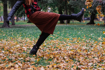 Sensual woman in a red bowler hat with long hair walking in park. Autumn fashion.