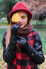 Sensual woman in a red bowler hat with long hair walking in park. Autumn fashion.
