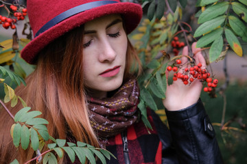 Sensual woman in a red bowler hat with long hair walking in park. Autumn fashion.