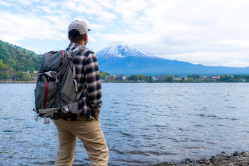 Young Boy Backpackers traveling Beautiful Fuji Mountain,  Men Backpacking Fujisan volcano at Kawaguchiko lake, Japan.