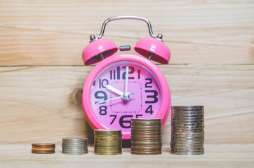 business and financial concept idea coin stacking and antique clock on wood table background for saving coin growth up wealthy successful for investment in future or save money for retirement.