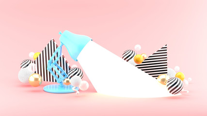 A table lamp emits light amid colorful balls on an pink background.-3d rendering.