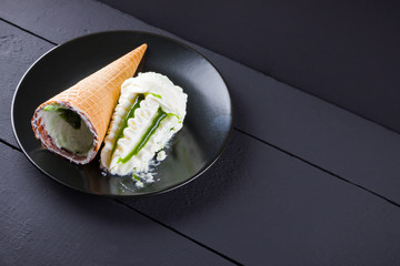 Ice cream cone on black background, summer concept. Dessert with jam on black plate. Waffle cone with ice cream in minimalism style. Copy space