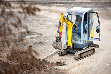 Tracked mini excavator breaks out old curbs before installing new curbs. The concept of using economical and compact equipment