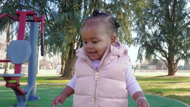 Black mixed race toddler girl at the park enjoying herself displaying different emotions.