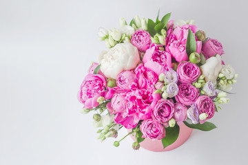 Arrangement of flowers in a hat box. Bouquet of peonies, eustoma, spray rose in a pink box with an oasis on a white background with copy space