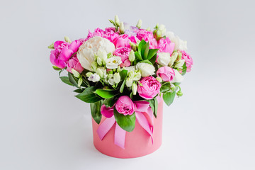 Obraz na płótnie Canvas Arrangement of flowers in a hat box. Bouquet of peonies, eustoma, spray rose in a pink box with an oasis on a white background