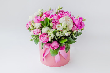 Arrangement of flowers in a hat box. Bouquet of peonies, eustoma, spray rose in a pink box with an...
