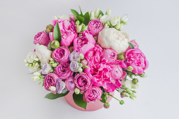 Arrangement of flowers in a hat box. Bouquet of peonies, eustoma, spray rose in a pink box with an oasis on a white background