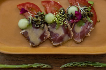 Tasty Rare seared Ahi tuna slices with fresh vegetable salad on a plate. Delicious seafood appetizer