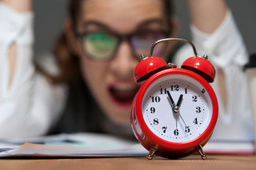 Portrait of hurried young businesswoman ooking at red retro styled clock