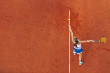 Aerial shot of a female tennis player on a court during match. Young woman playing tennis.High angle view.