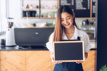 Pretty young asian waitress standing arms crossed in cafeteria.Coffee Business owner Concept.  barista in apron smiling at camera in coffee shop counter