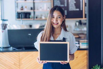 Pretty young asian waitress standing arms crossed in cafeteria.Coffee Business owner Concept.  barista in apron smiling at camera in coffee shop counter