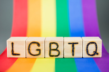 word lgbtq wooden cubes letters, on the background lgbt flag colors