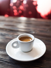 Coffee in a white cup stands on a wooden table.