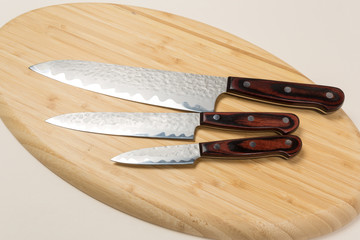 Several different used stainless steel kitchen knives with brown wooden handles