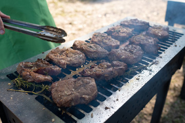 Grilling pork meat with barbecue stuff. Horizontal close up shot with a selective focus