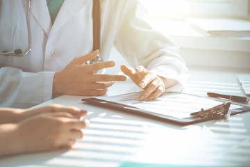 Doctor and patient are discussing something in clinic, just hands at the desk. Medicine and best service concept