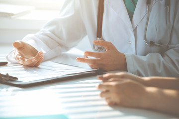 Doctor and patient are discussing something in clinic, just hands at the desk. Medicine and best service concept