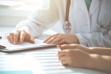 Doctor and patient are discussing something in clinic, just hands at the desk. Medicine and best service concept