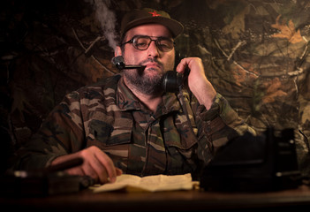 The evil dictator sitting on table. Angry communist general sitting at headquarter or Cuban...