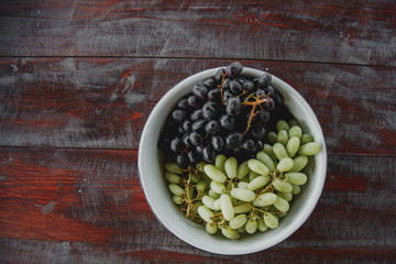 a plate with blue and white grapes stands on a dark wooden table