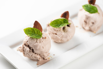 Hazelnut ice cream with nuts on a white plate and white background