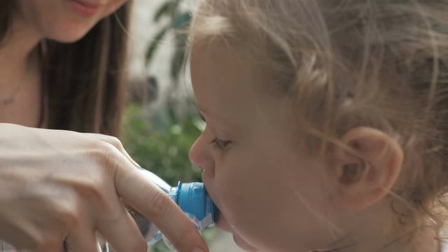 mom gives the child water from the bottle
