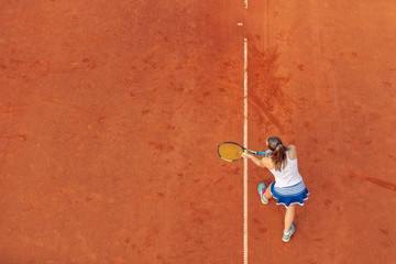 Aerial shot of a female tennis player on a court during match. Young woman playing tennis.High angle view.