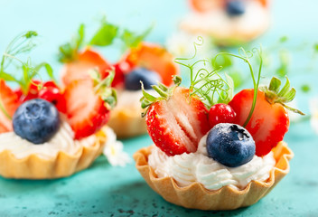 Summer berry tartlets  with cream and fresh berries.