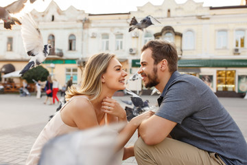 Young couple in love looking at each other against the background of flying pigeons in the city