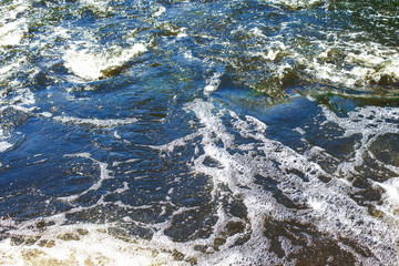 Water foam texture. Blue bubble spa washing background. Rough river water on a dam backdrop.