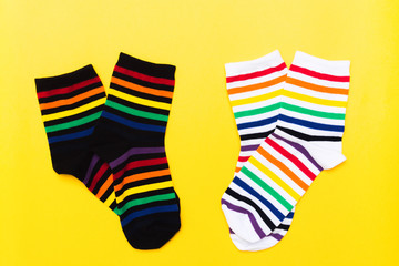 Two pair of black and white textile cotton socks with striped bright colorful pattern over yellow background