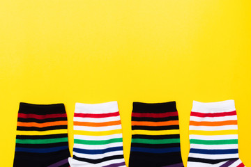 Four black and white socks with colorful striped background over yellow background