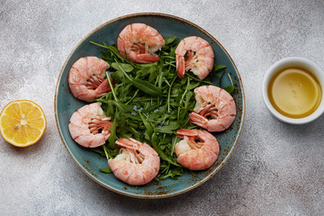 Ingredients for simple shrimp salad: shrimps, arugula, lemon and olive oil. Top view
