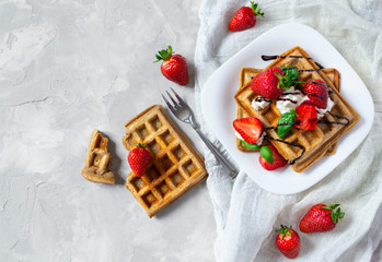 Waffles with strawberries, ricotta cheese and chocolate on white plate. Top view.