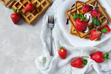 Belgium waffles with strawberries, ricotta cheese and chocolate on white plate. Top view. Copy space