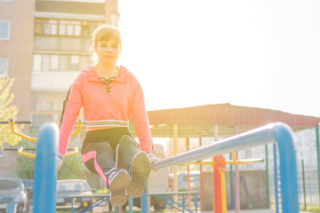 woman raises her legs on uneven bars