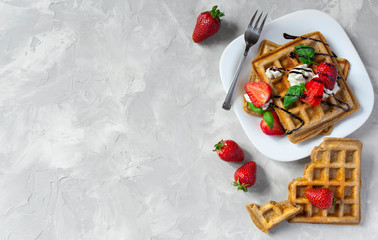 Belgium waffles with strawberries, ricotta cheese and chocolate on white plate. Top view. Copy space