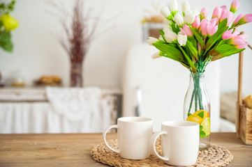 Breakfast cups and fruit. Spring tulips on the table. Wooden table in a bright rustic-style...