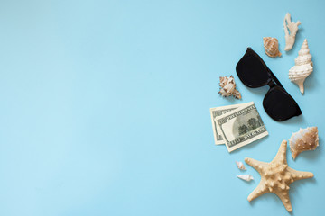 Flat lay traveler accessories on blue background , copy space with sea shells, money and sunglasses. Top view . Summer background.