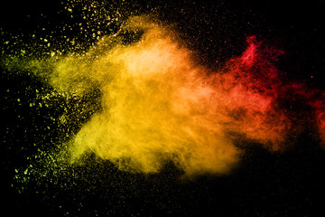 Abstract yellow orange powder explosion on black background.Freeze motion of color dust splash.